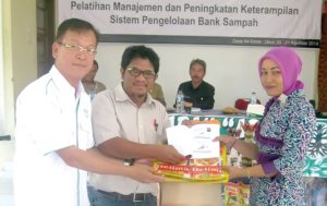 Asian Agri's Head of Sustainability and CSR Welly Pardede hands out a waste management guidebook to a trash bank management trainee